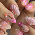 Handmade pink floral press-on nails with gold leaf, pearls, and gem accents