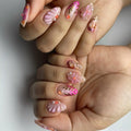 Handmade pink press-on nails with 3D floral designs, gold leaf accents, and pearl embellishments.