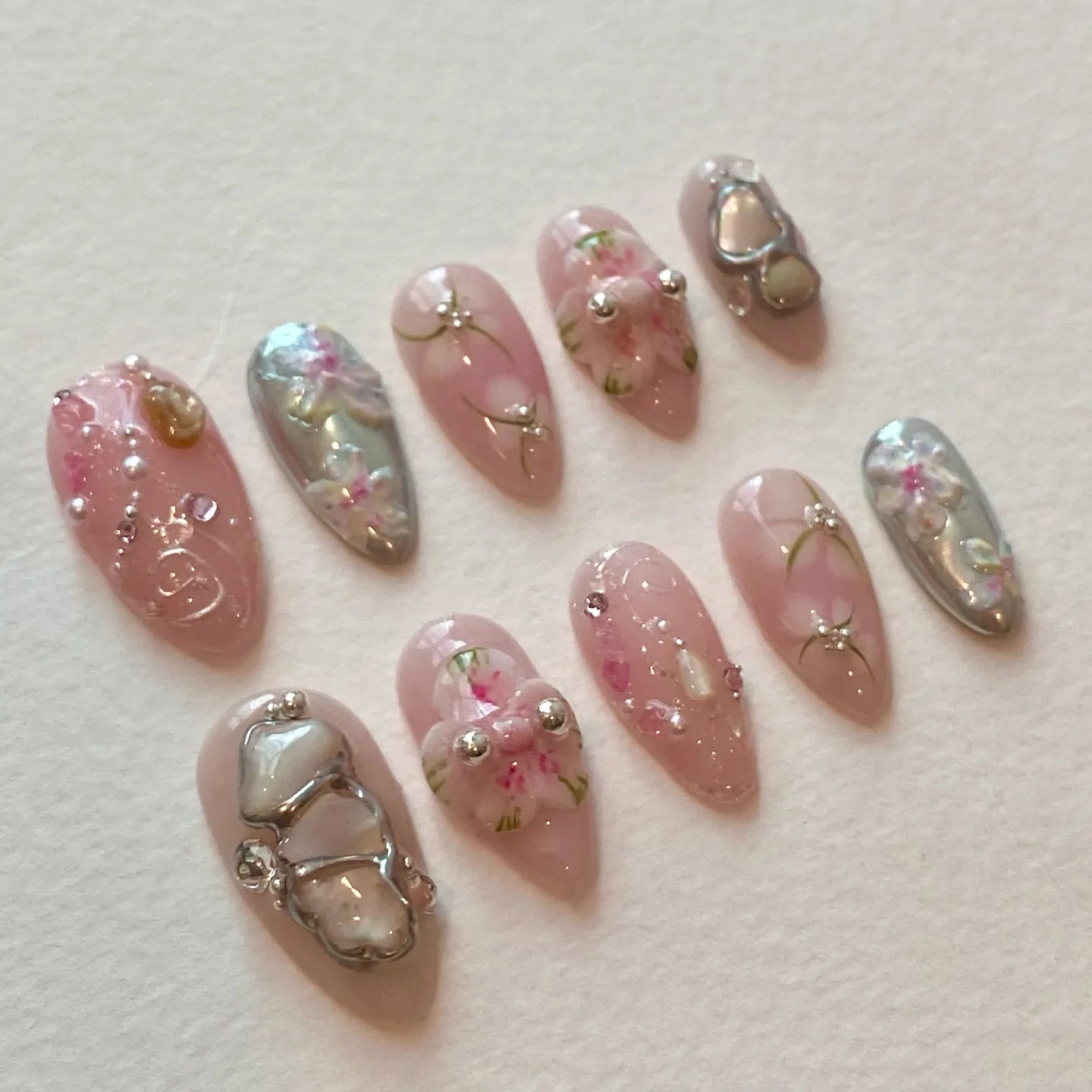 Handmade pink and silver chrome press-on nails with 3D flower, jewel, and glamour charms.