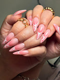 Hand with long almond-shaped press-on nails in pink swirl abstract French tip design