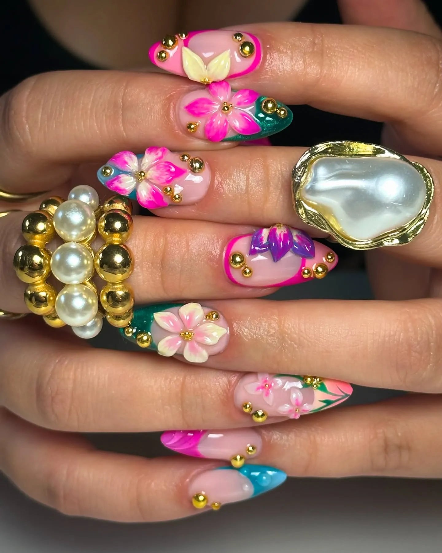 Hand with handmade 3D floral press-on nails in pink, teal, and gold caviar accents.
