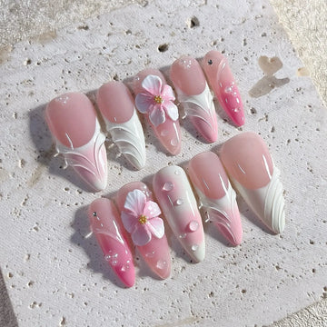 Handmade press-on nails with pink and white ombre, 3D floral accents, and water drop gems.