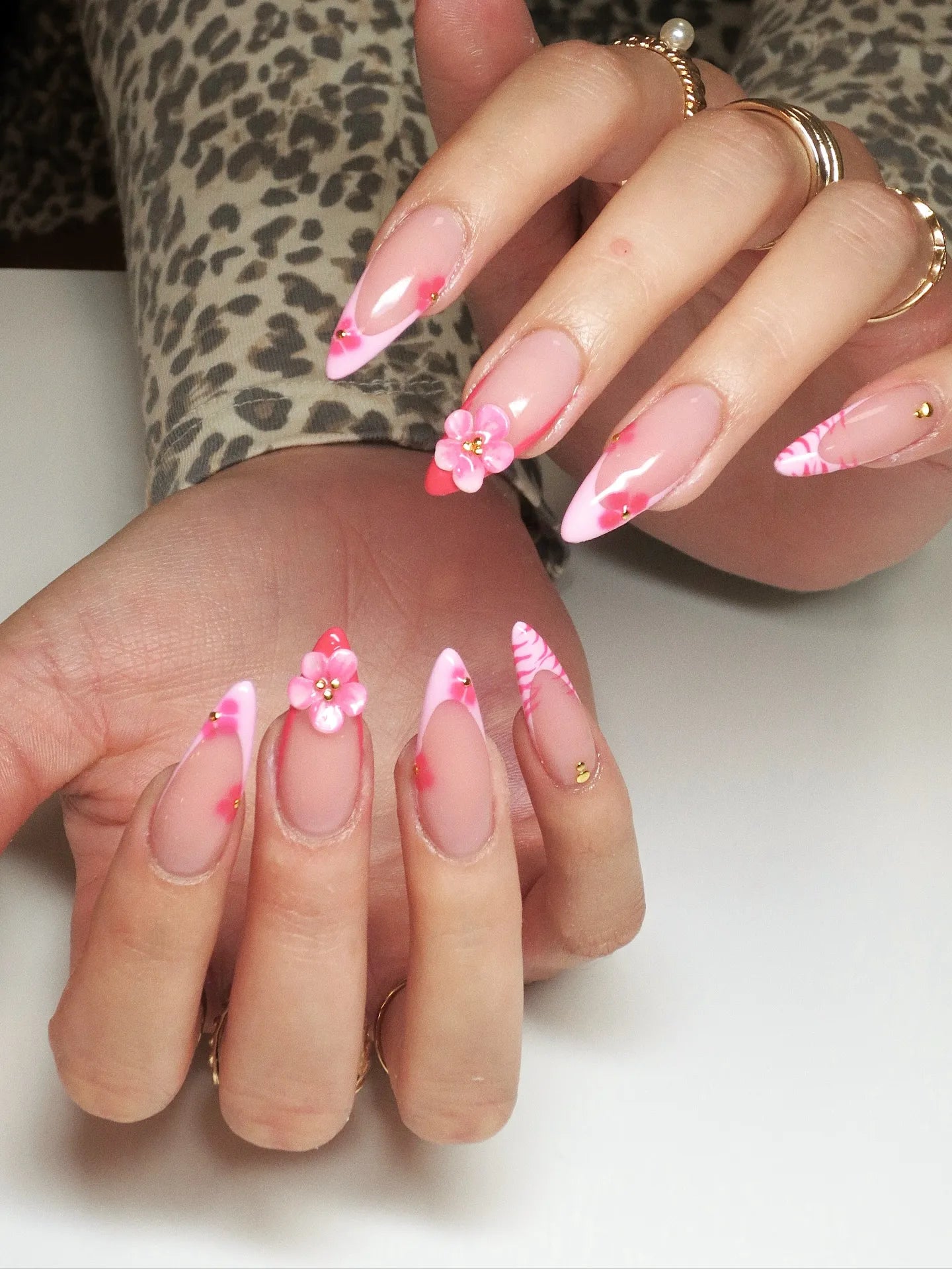 Hand with handmade pink zebra French tip press-on nails, 3D floral and gem accents.
