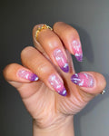 Hand with handmade pink, purple, and silver shimmering dreamy cloud press-on nails