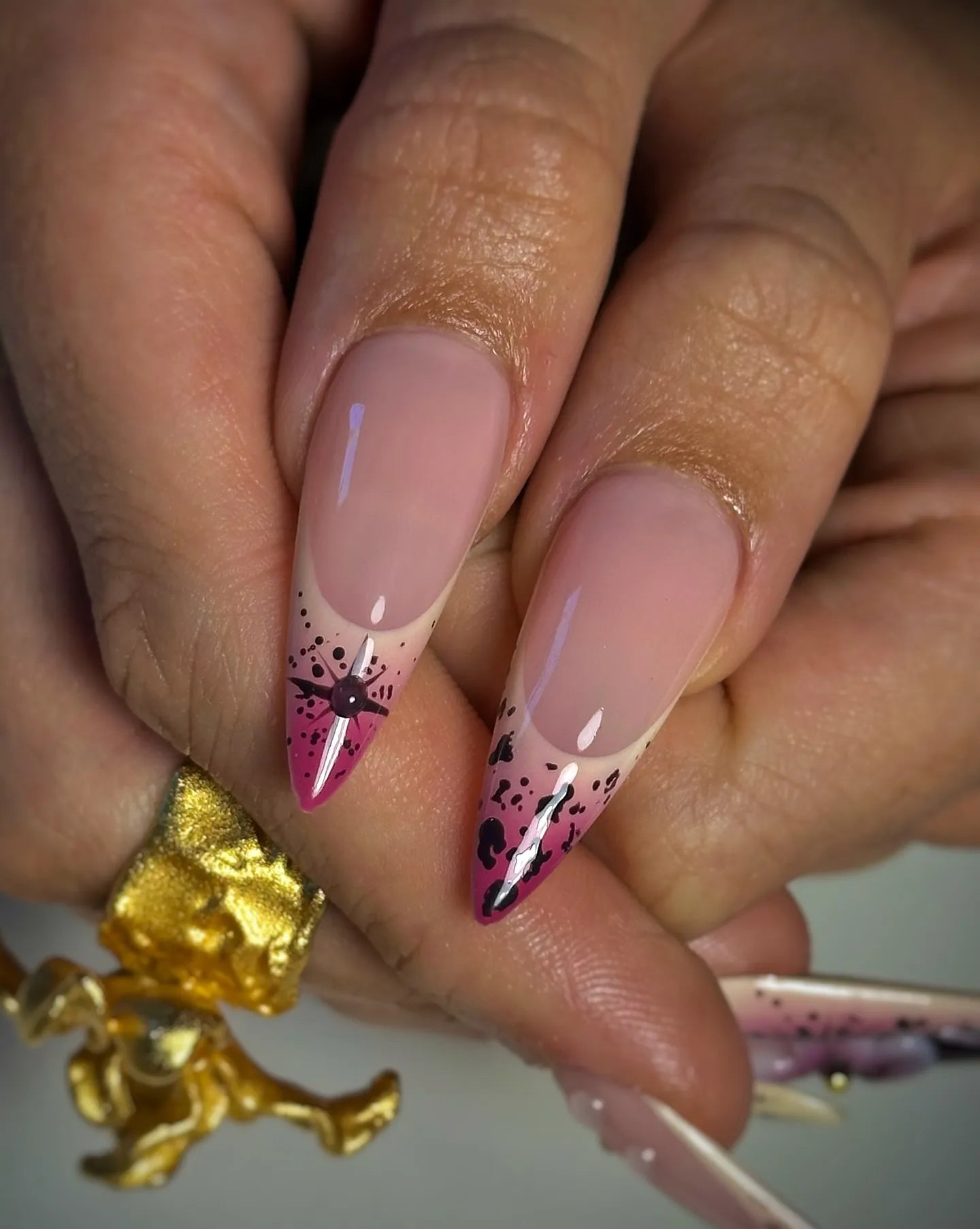 Hand holding handmade stiletto press-on nails with purple galaxy and star floral art.