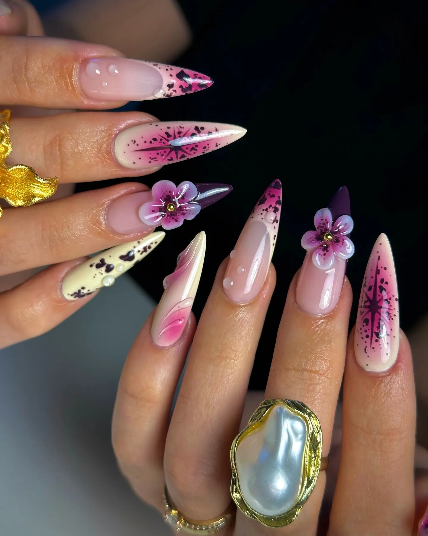 Hand with handmade purple floral celestial 3D press-on nails with star and galaxy designs.