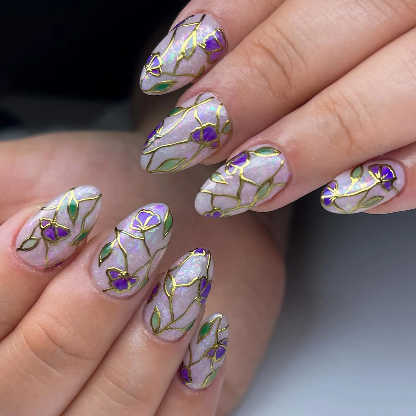 Handmade press-on nails featuring purple floral stained glass design with gold foil accents.