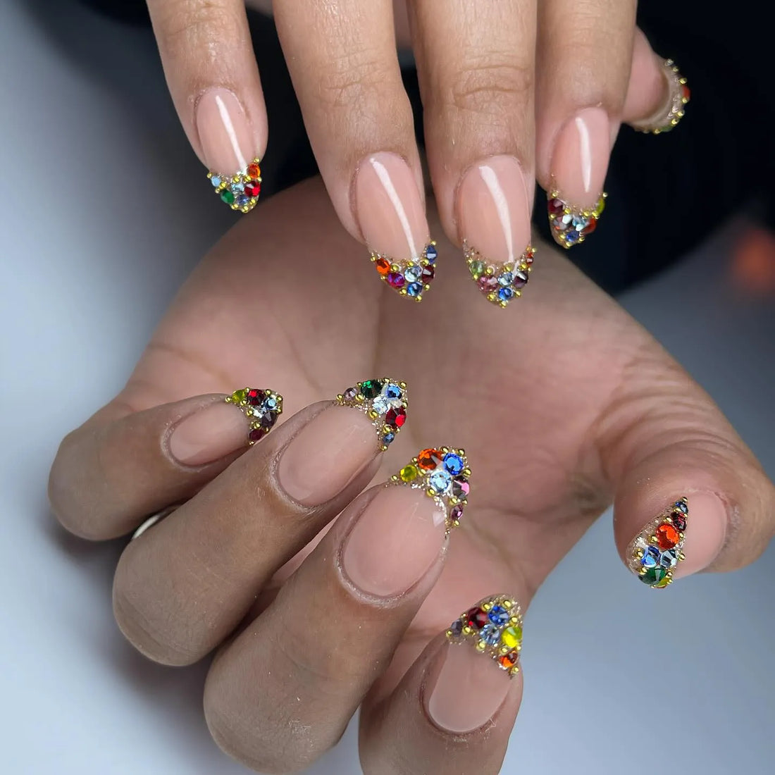 Handmade nude press-on nails with rainbow crystal French tips and jewel accents