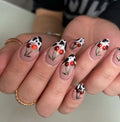 Handmade press-on nails with red cherry art and black cow print tips