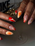 Hand with handmade red and orange tropical floral press-on nails, mermaid and shell details.