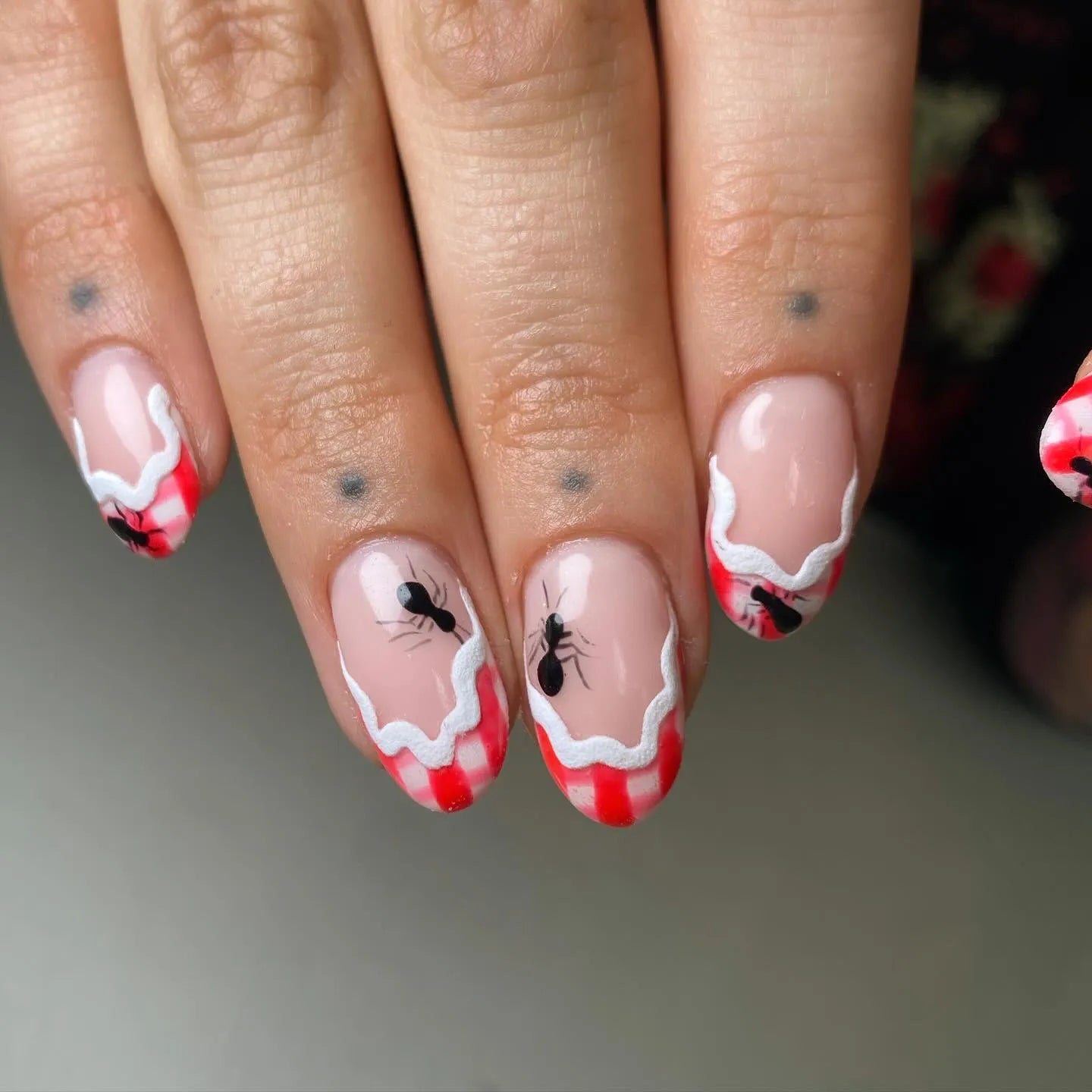 Handmade press-on nails with red gingham French tips and ant picnic nail art design.
