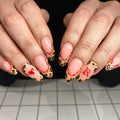 Hand with almond-shaped press-on nails, red lace French tips, leopard print and heart design.