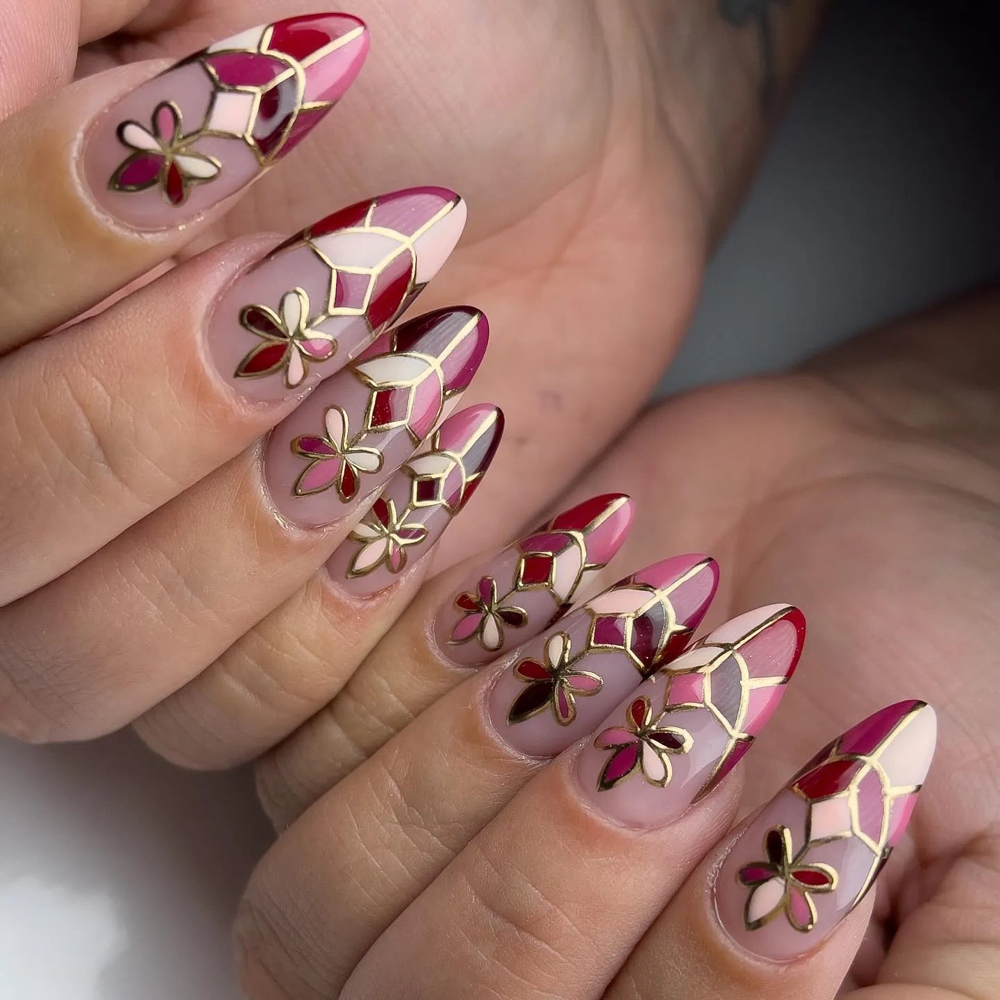 Handmade press-on nails with red mosaic, gold outline, and floral designs
