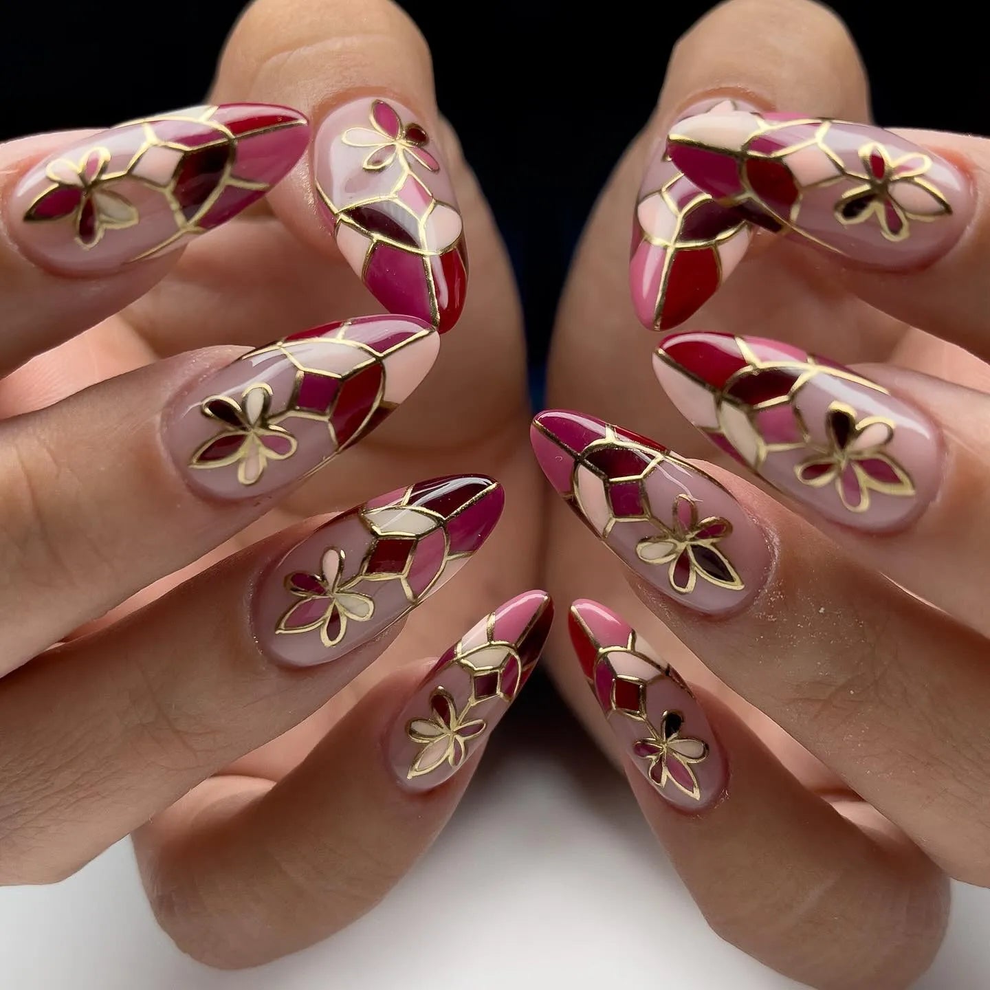 Handmade press-on nails with red mosaic, gold outlines, and floral designs.