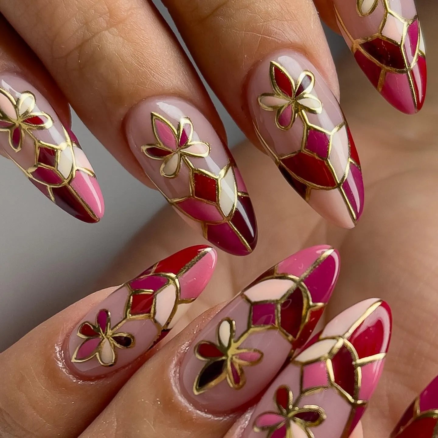 Handmade press-on nails with red mosaic floral design and gold outlines, almond shape