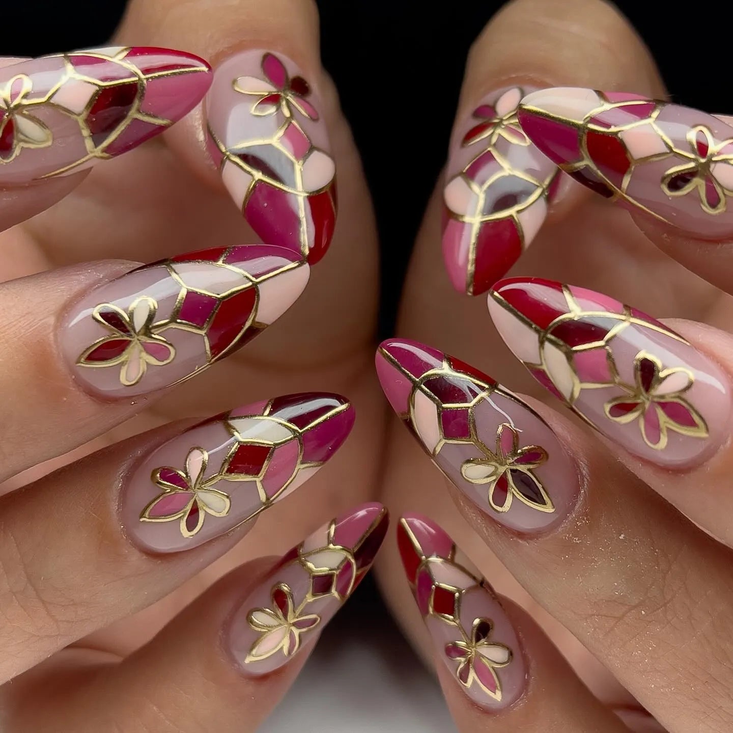 Handmade red mosaic floral press-on nails with gold outline and pink accents.