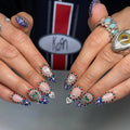 Handmade royal blue ombre heart press-on nails with colorful chrome gemstones.