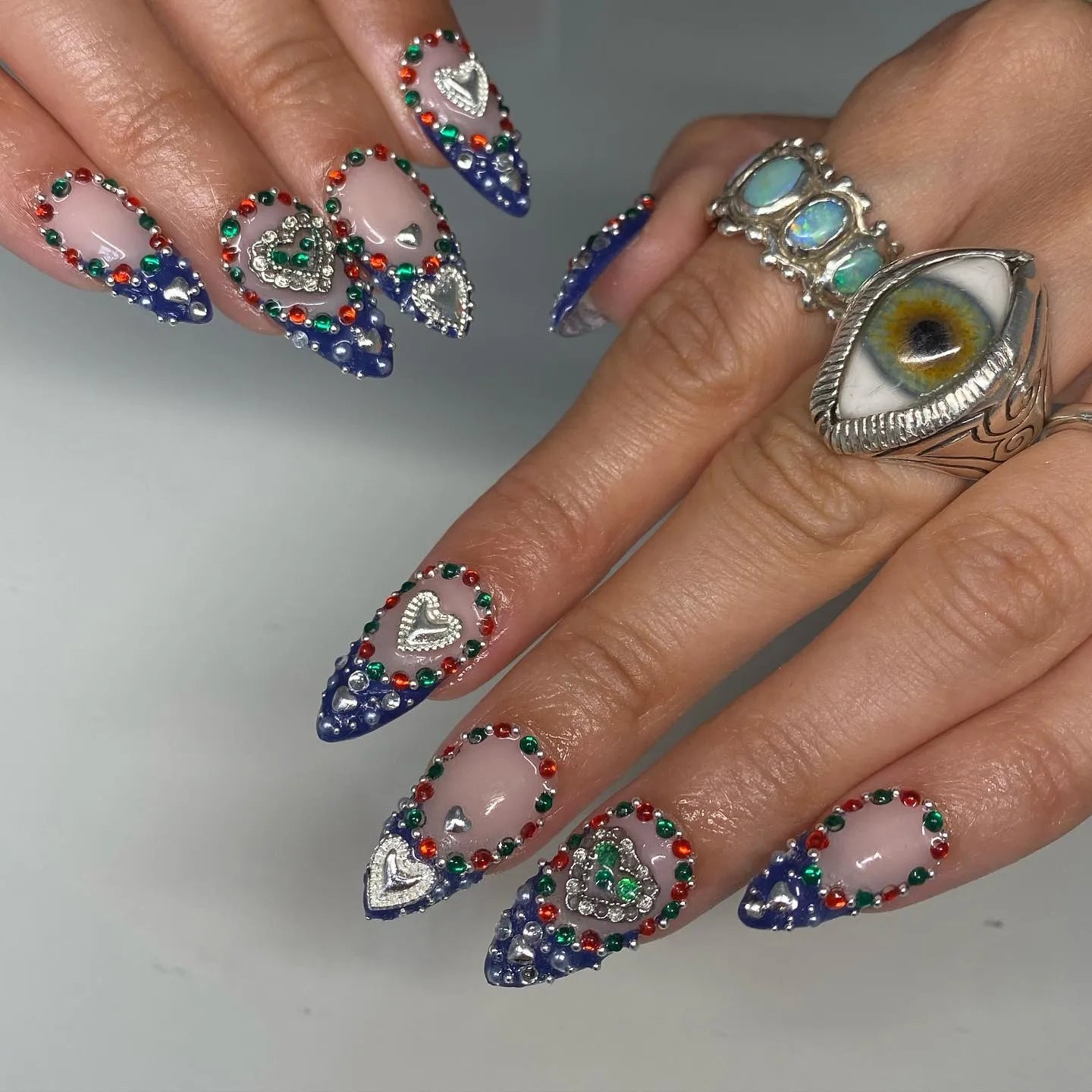 Handmade royal blue ombre press-on nails with heart charms, rhinestones, and gemstone details.