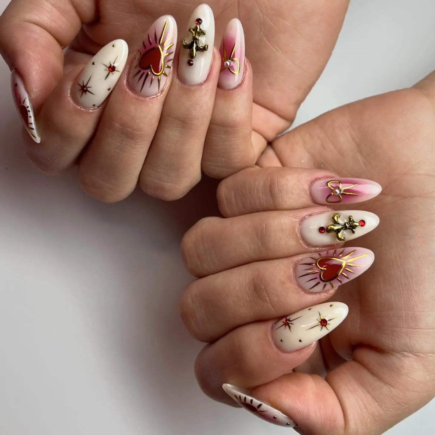 Handmade press-on nails with gold fleur-de-lis, red sacred heart, and star designs.