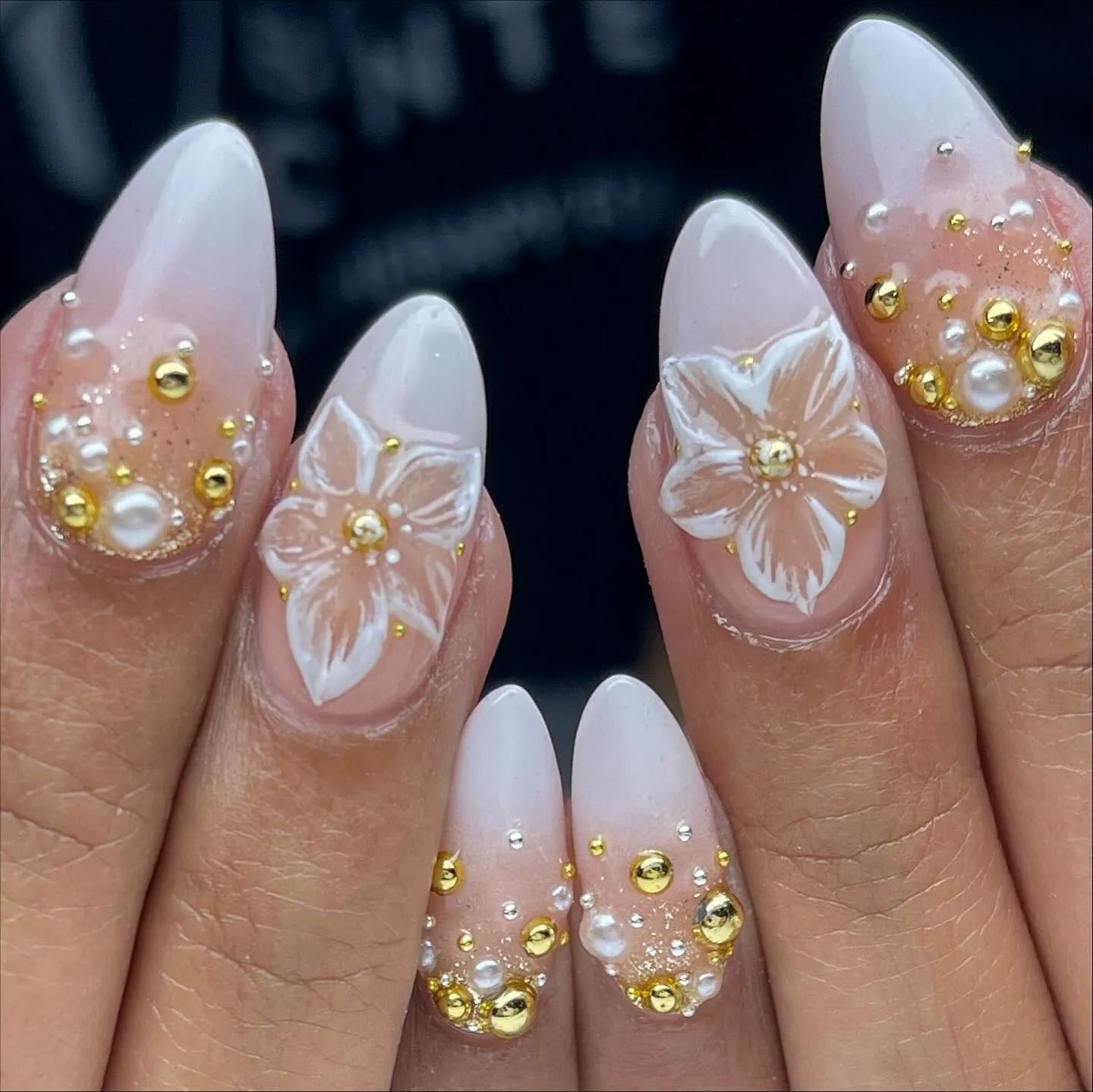 Handmade press-on nails with white 3D floral designs, gold beads, and pearl accents.