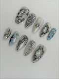 Handmade silver metallic cyber shell liquid chrome press-on nails set on white background