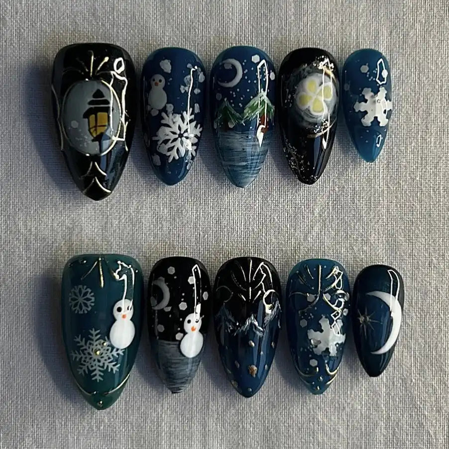 Handmade dark blue snowy winter press-on nails with snowmen, snowflakes, moon, and lantern designs.