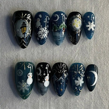 Handmade dark blue snowy winter press-on nails with snowmen, snowflakes, moon, and lantern designs.