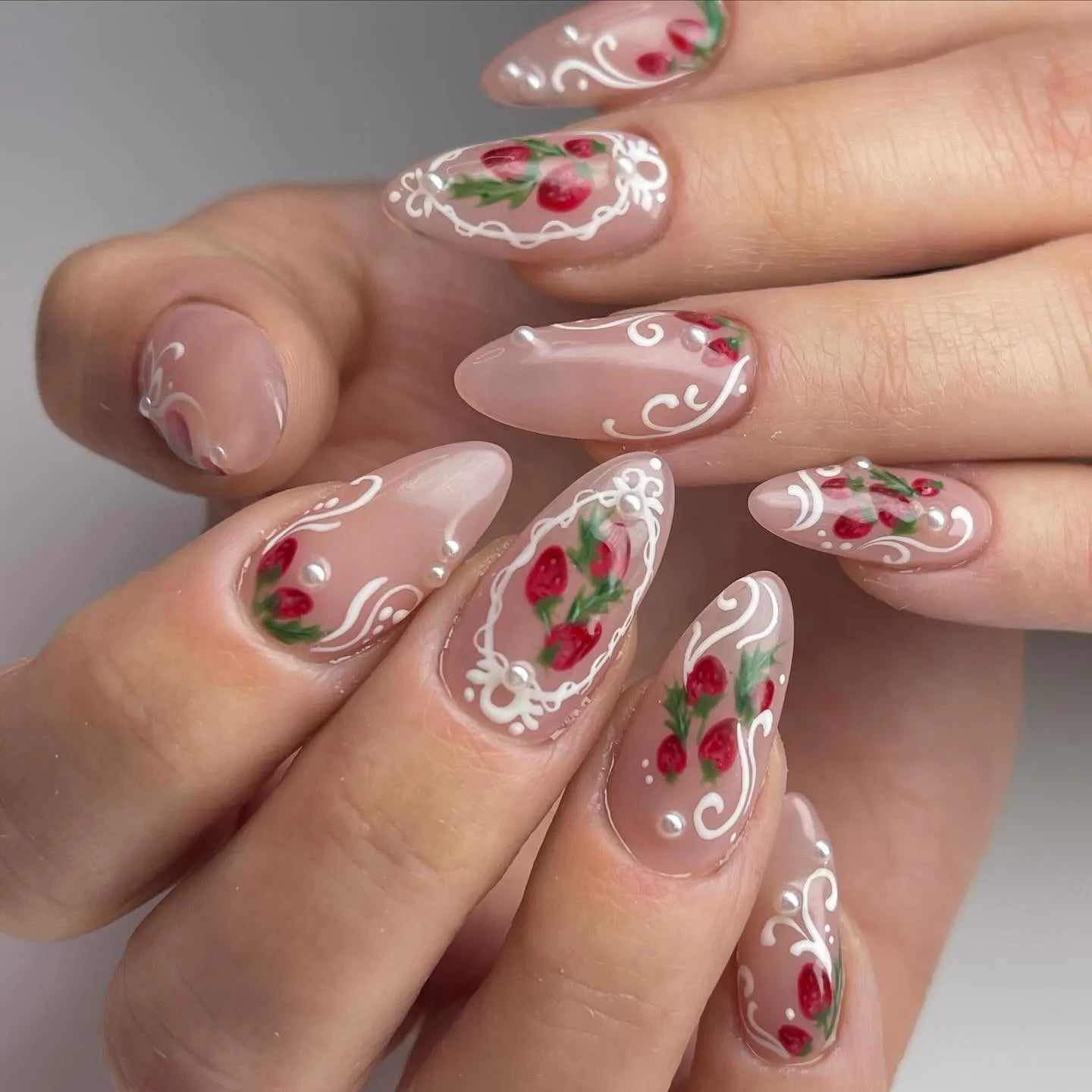Handmade press-on nails with strawberry art, white lace French tips, and pearl accents.