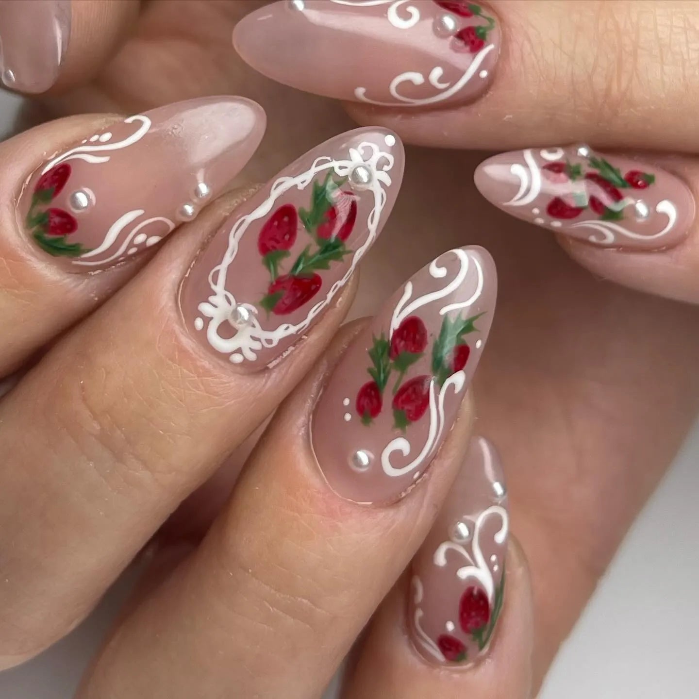 Handmade press-on nails with strawberry art, white lace tips, and pearl accents