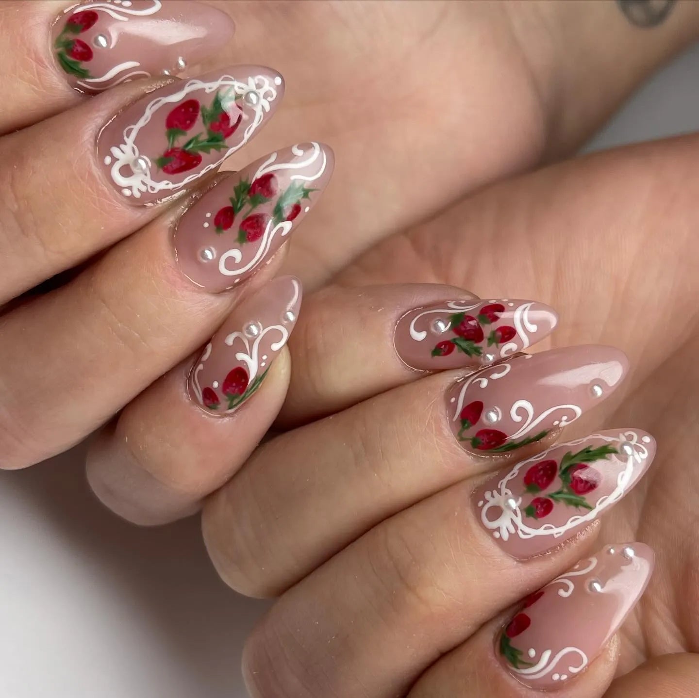 Handmade press-on nails with strawberry art, white lace French tips, and pearl accents.