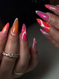 Handmade press-on nails with pink, orange, and white sunset gradient and star designs