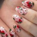 Hand-painted press-on nails with pink base, strawberry and floral summer nail art design.