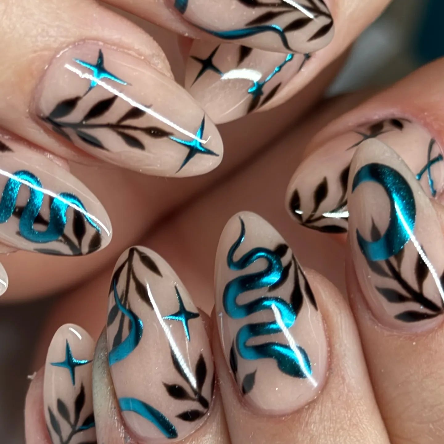 Handmade press-on nails with teal chrome snake, moon, leaves, and star designs