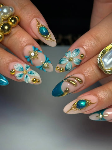 Handmade press-on nails with teal, gold celestial designs and 3D floral accents.