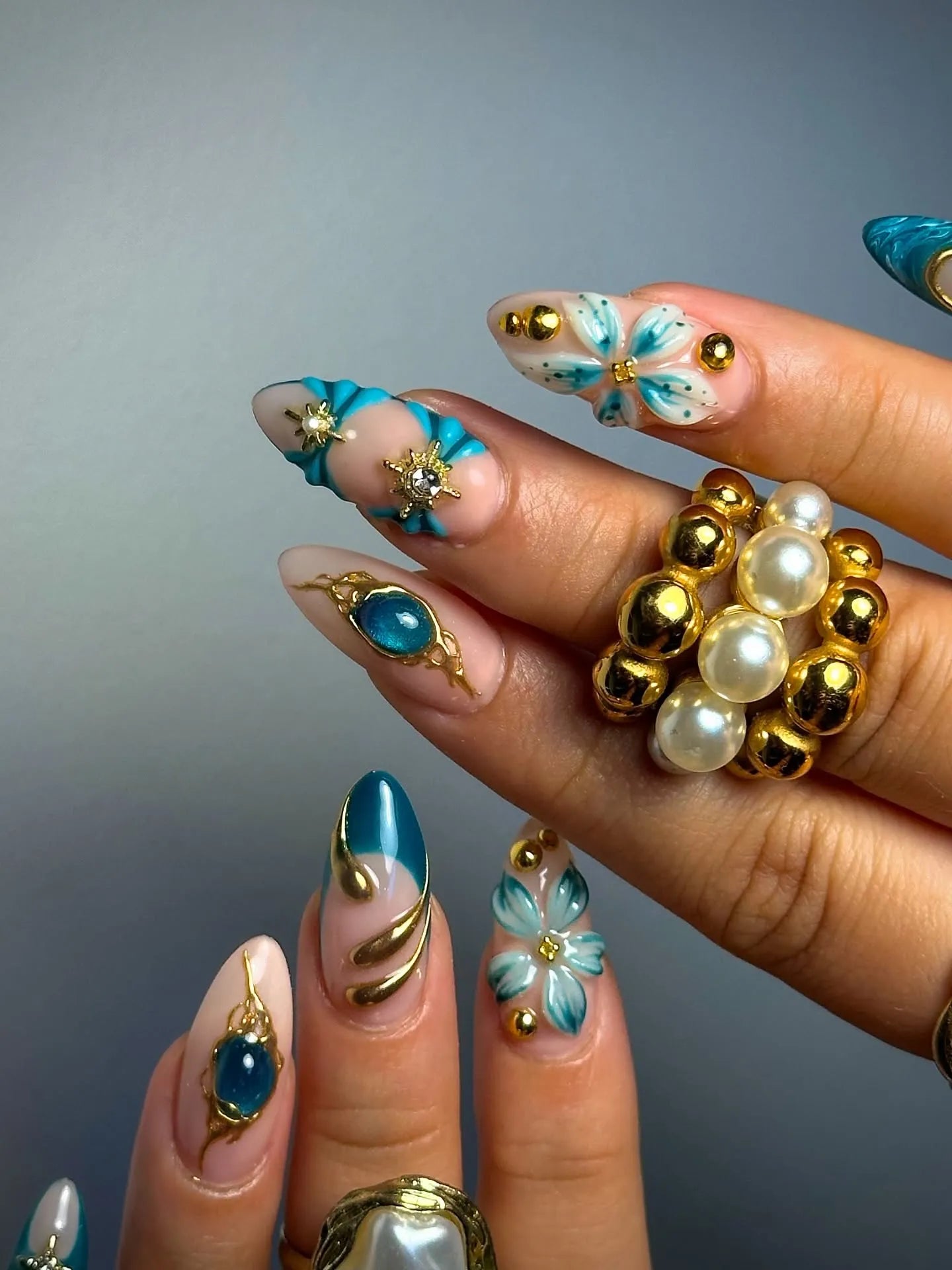 Handmade teal and gold 3D floral press-on nails with jeweled celestial accents