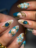 Handmade press-on nails with teal and gold 3D floral, celestial, and jewel designs