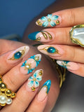 Handmade teal and gold press-on nails with 3D floral and celestial designs, luxury accents.