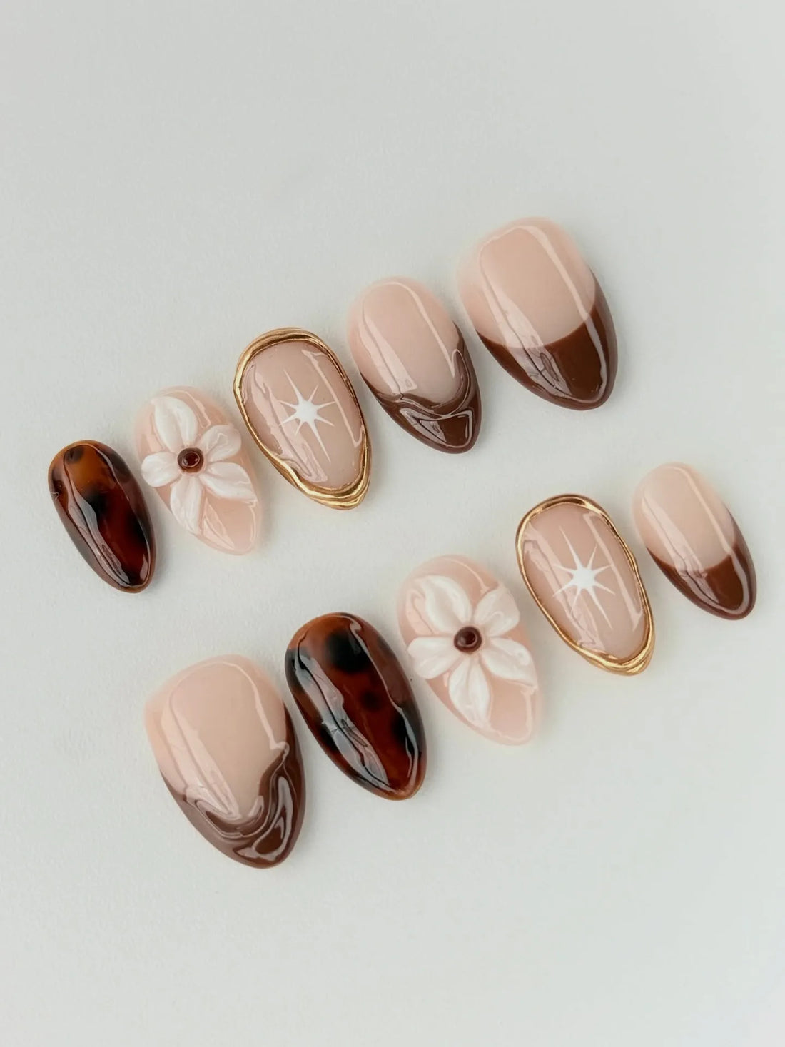Handmade press-on nails with tortoise shell, 3D floral, brown French tips, and gold accents.