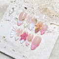 Handmade tropical press-on nails with 3D hibiscus and seashell designs in pink and nude tones.