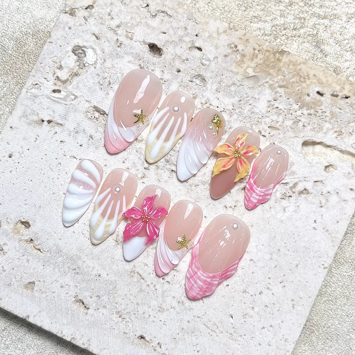 Handmade tropical press-on nails with 3D hibiscus and seashell designs in pink and nude tones.