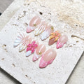 Handmade tropical press-on nails with 3D shell and hibiscus flower designs in pink and white.