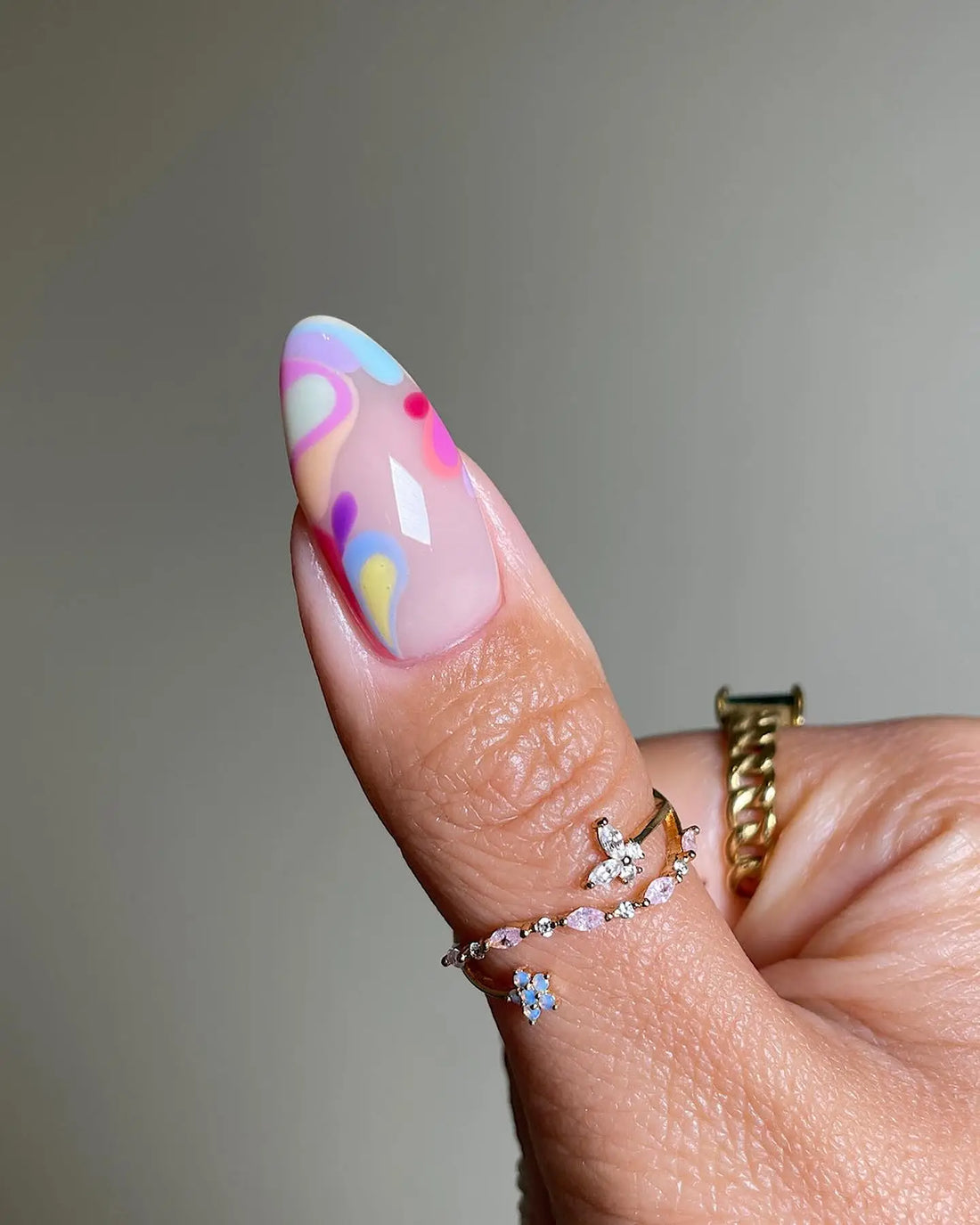 Hand with handmade tropical press-on nails featuring orchid, papaya, and botanical designs.