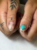 Handcrafted press-on nails with turquoise heart, gold sunburst, and celestial designs.