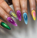 Hand with long, vibrant rainbow chrome press-on nails featuring liquid drip accents