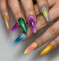 Hand with pointed, handmade press-on nails in vibrant rainbow chrome and drip designs
