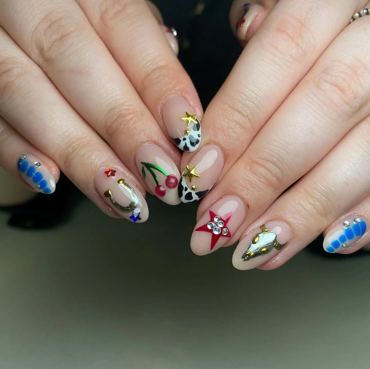 Handmade Western cowgirl press-on nails with cow print, cherries, horseshoes, stars, and 3D accents.