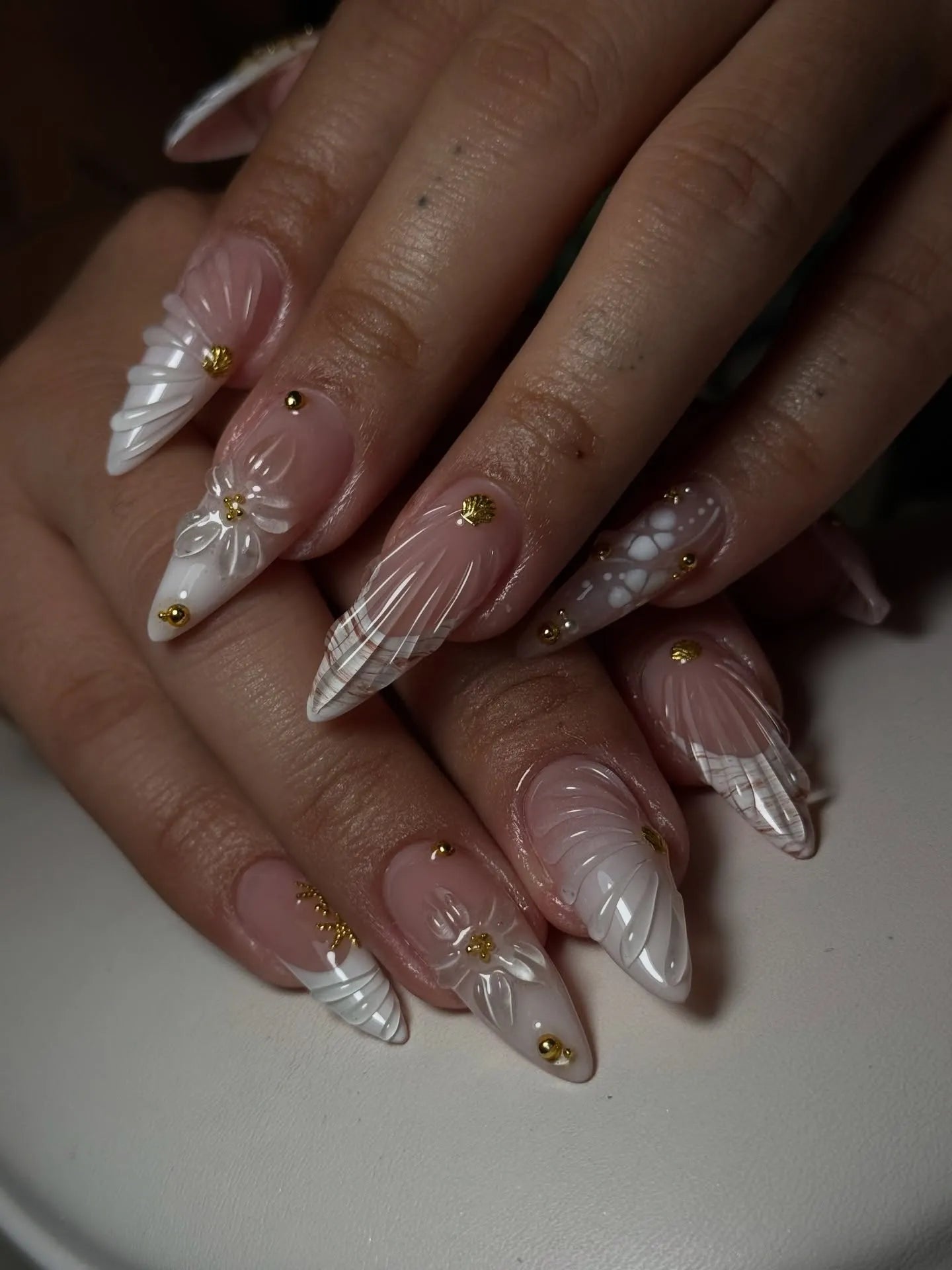 Handmade white 3D shell floral press-on nails with gold stud accents, long stiletto shape.
