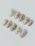 Handmade press-on nails with white pearls, gold celestial moon and star designs on pink and white base.