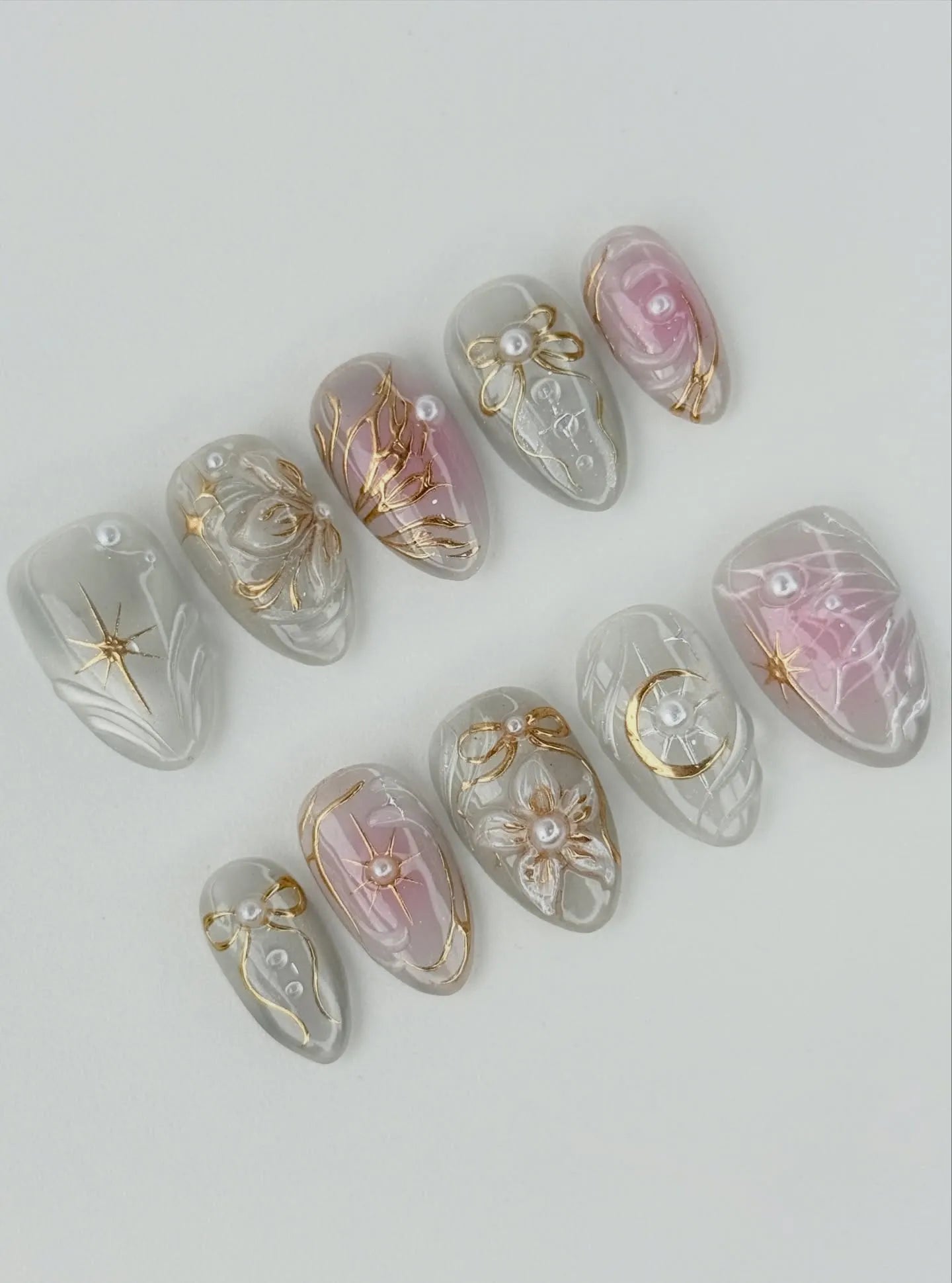 Handmade press-on nails with white pearls, gold crescent moon, stars, and floral accents.