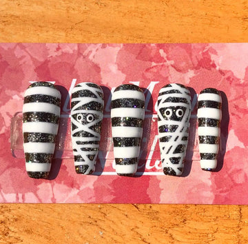Handmade Halloween press-on nails with black glitter and white mummy wrap design